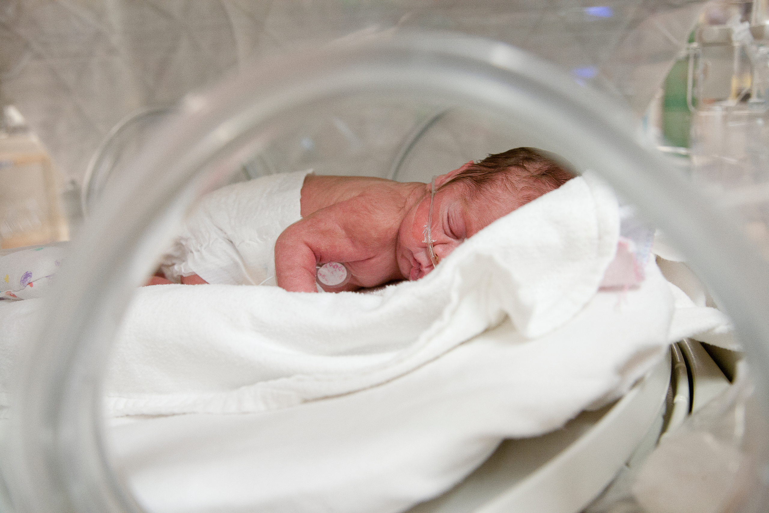 Mom breastfeeding a premature baby in a neonatal unit.