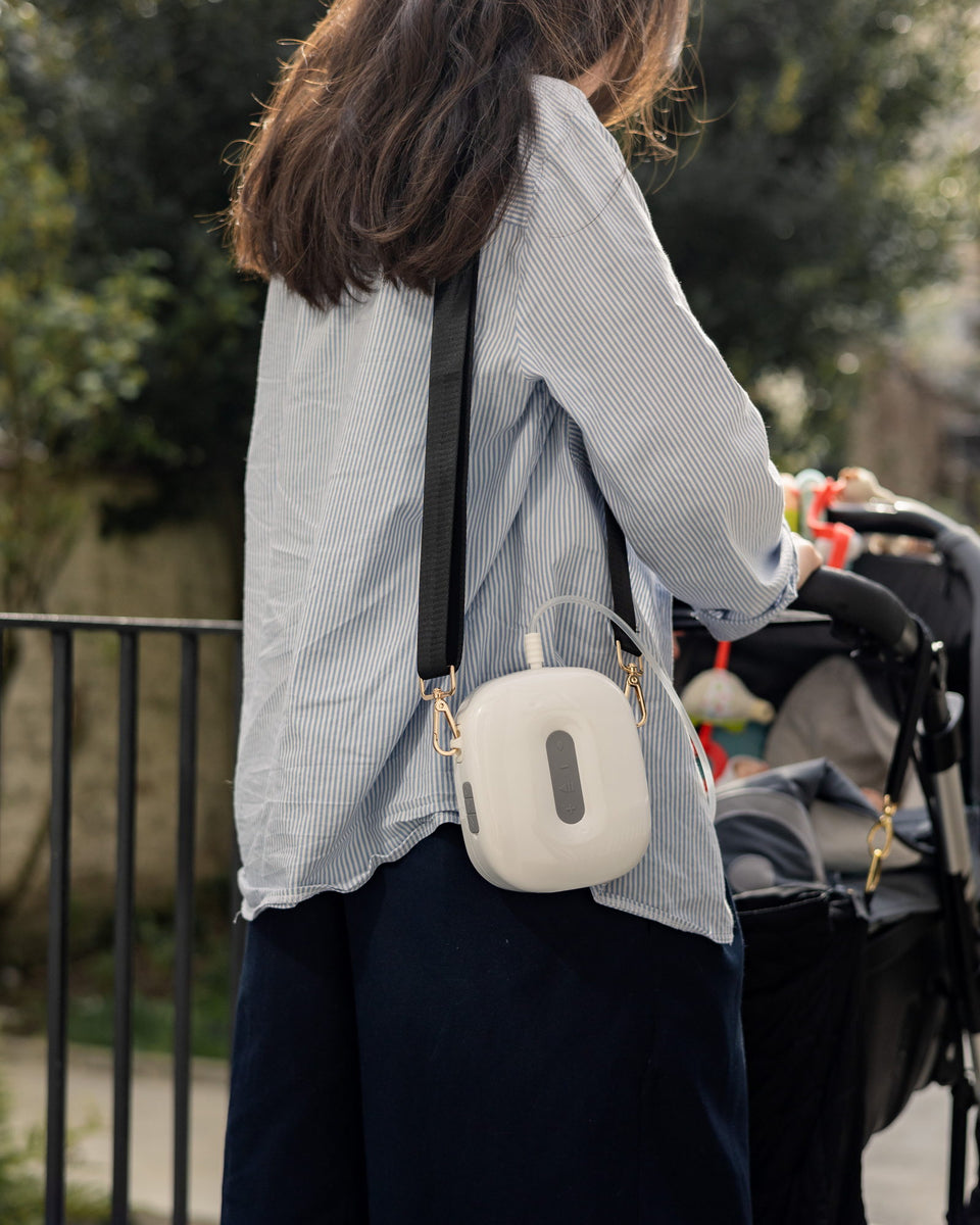 A mother out with the pushchair, the Lileo breast pump worn across the body.