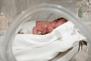 Een moeder die een premature baby borstvoeding geeft op een couveuseafdeling.